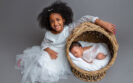 newborn in a basket big sister with arm around