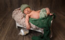 adorable newborn baby boy on bed prop with bottle of milk