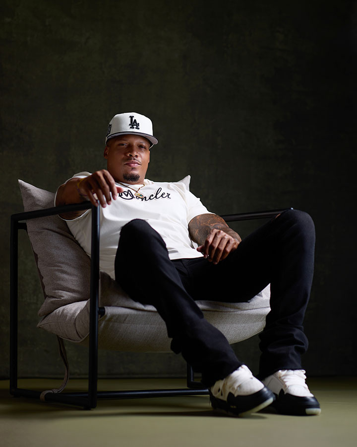 Black man posing in a chair with green textured background