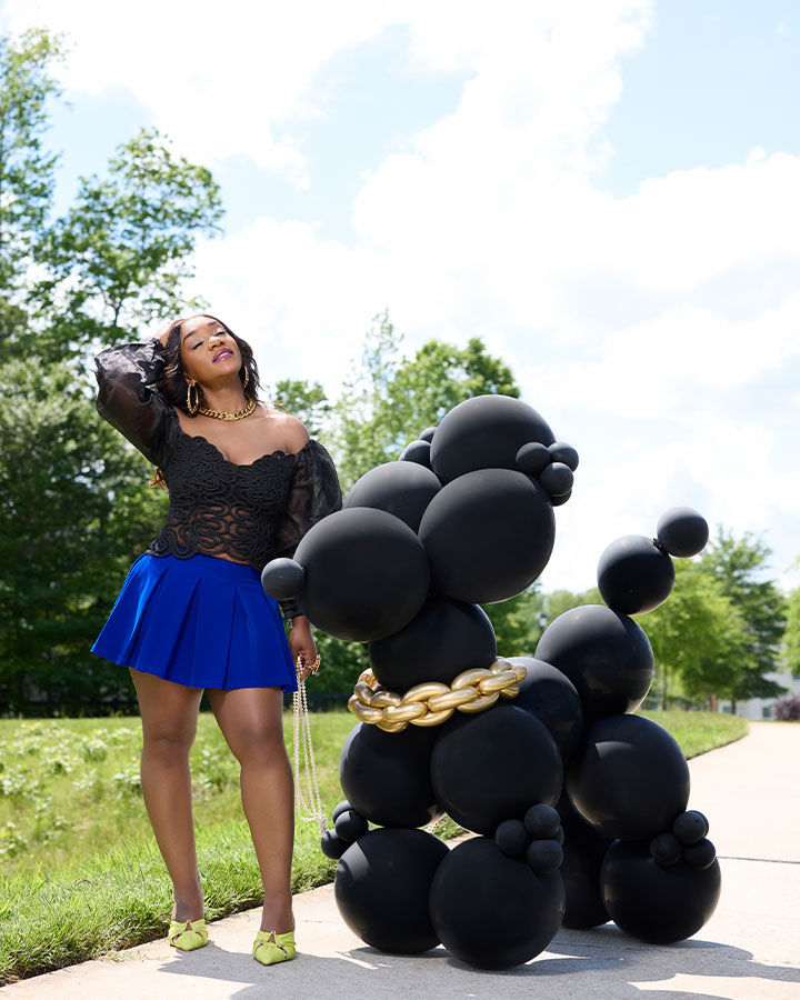 Woman posing outside with a gian balloon dog